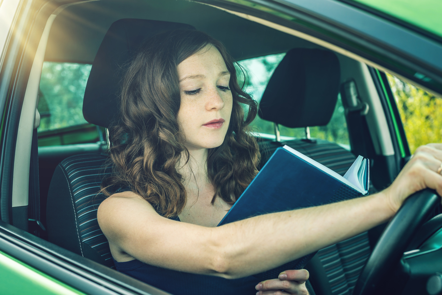 Driving reading. Чтение книги за рулём. Reading in a car. Reading book in the car. Девушка нарушает правила.